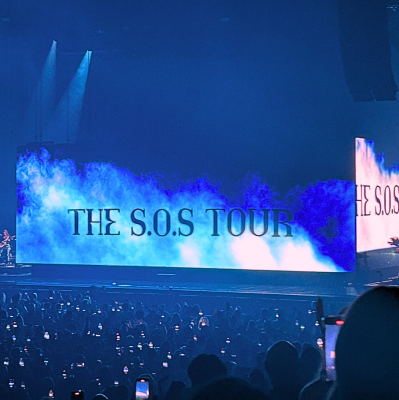 Intro to SZA concert for SOS tour. Screens on stage project the writing, The SOS Tour in blue lights.